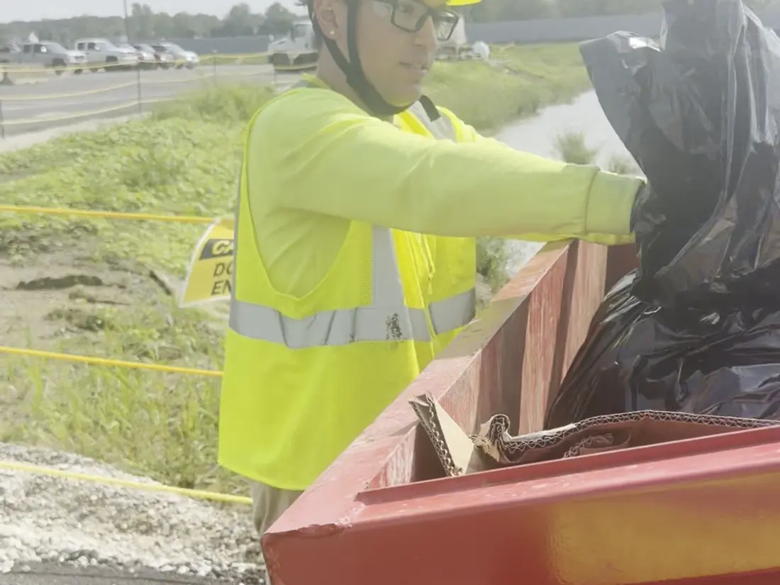 A crew member emptying collected litter into a receptacle.