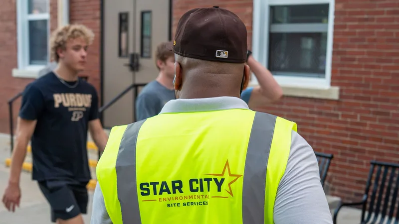 A Star City Environmental crew member in a branded vest outside a commercial building.