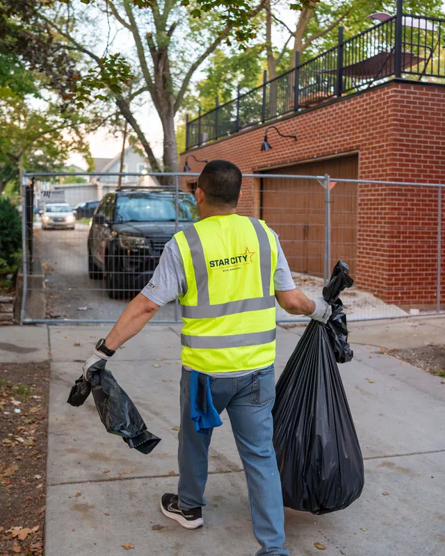 A crew member walking a property line with collected waste bags.