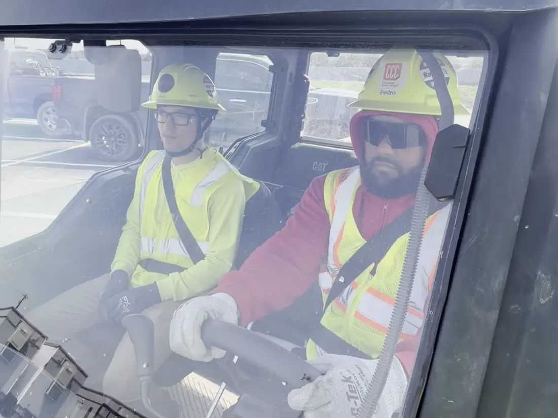 Two Star City Environmental crew members in hard hats in a site vehicle.