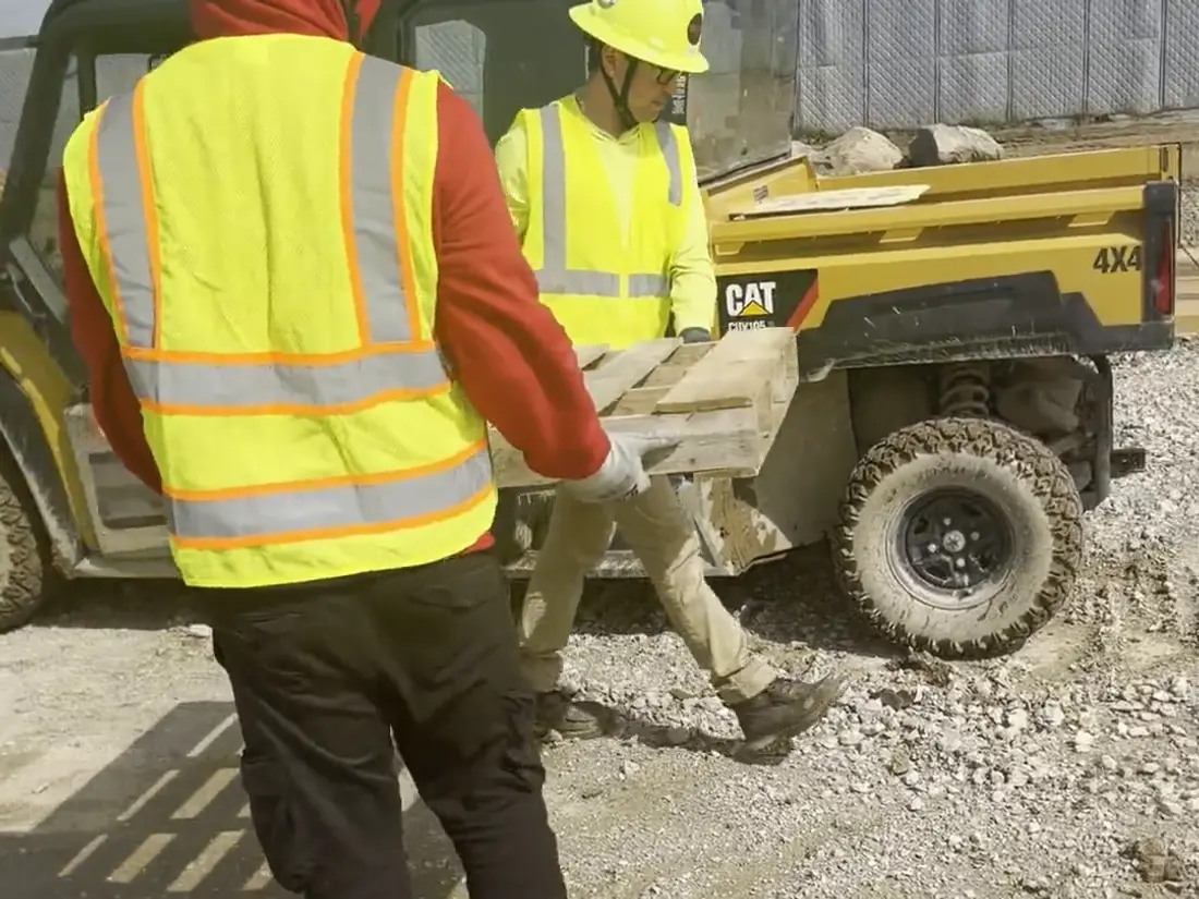 Two Star City Environmental crew members carrying material to the site vehicle on a construction site.