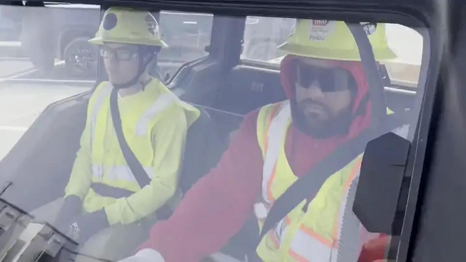 Two Star City Environmental crew members in hard hats in a site vehicle.