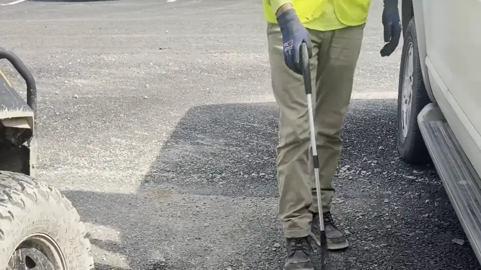 A crew member walking a parking lot collecting litter.