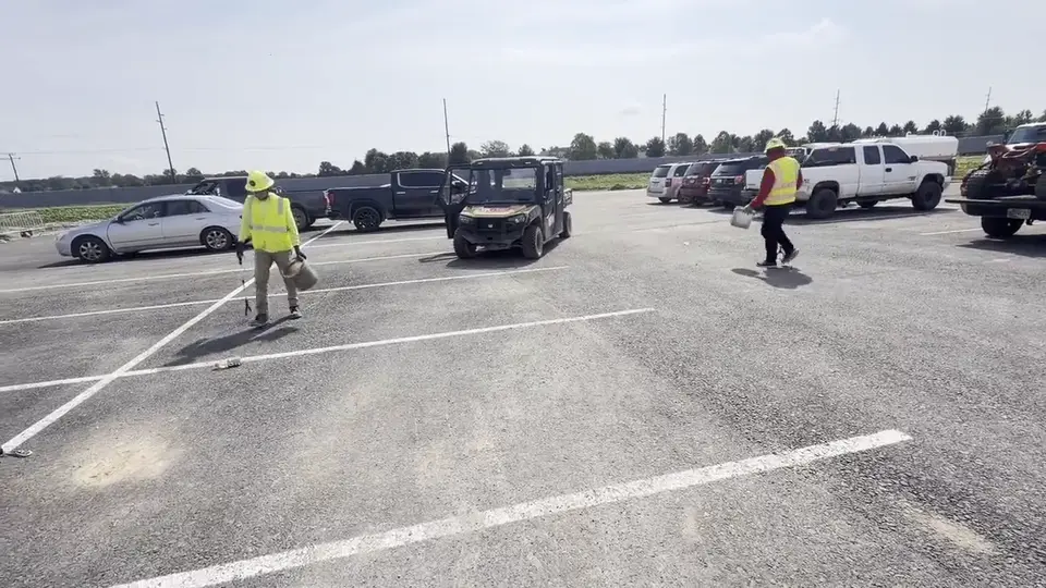 Crew clearing litter across a wide paved lot.